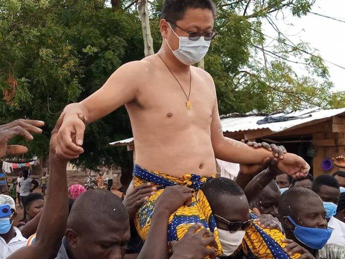 Chinese man carried by African men in chief ceremony