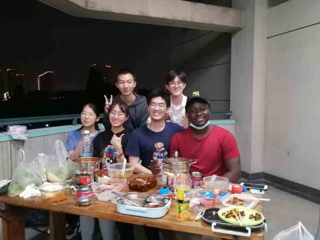 Ghana college student sitting to eat with Chinese friends